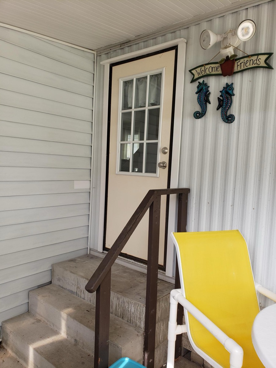 Carport entry door with covered breezeway and welcome décor