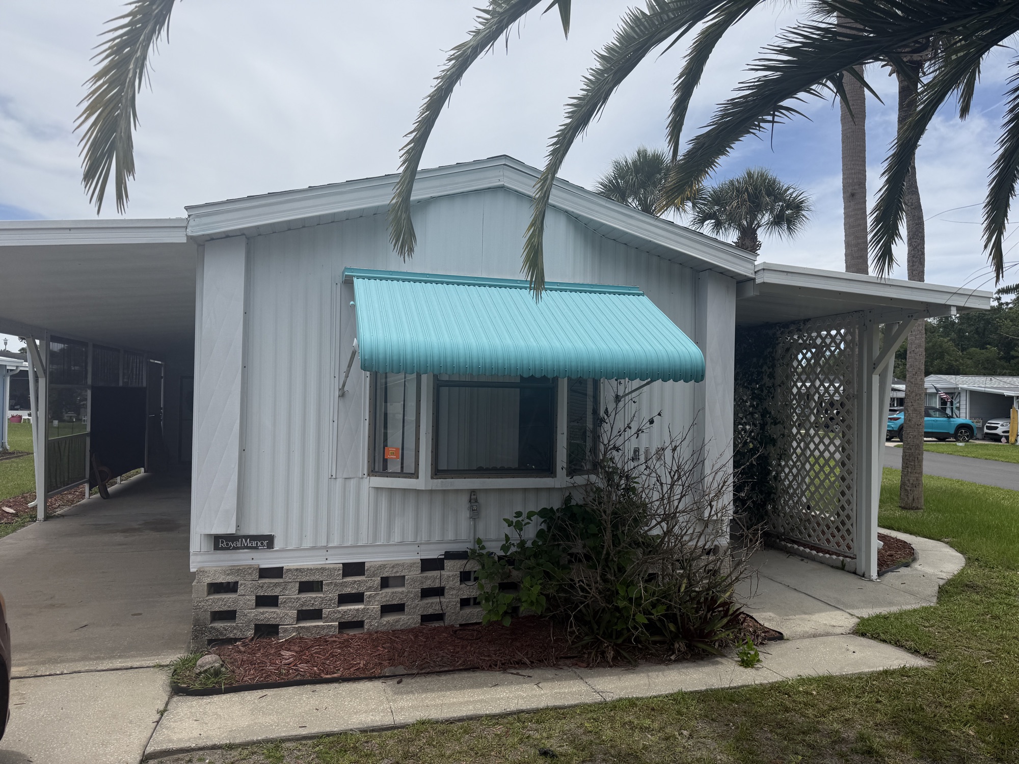 Front of the home with its signature teal awnings and palms