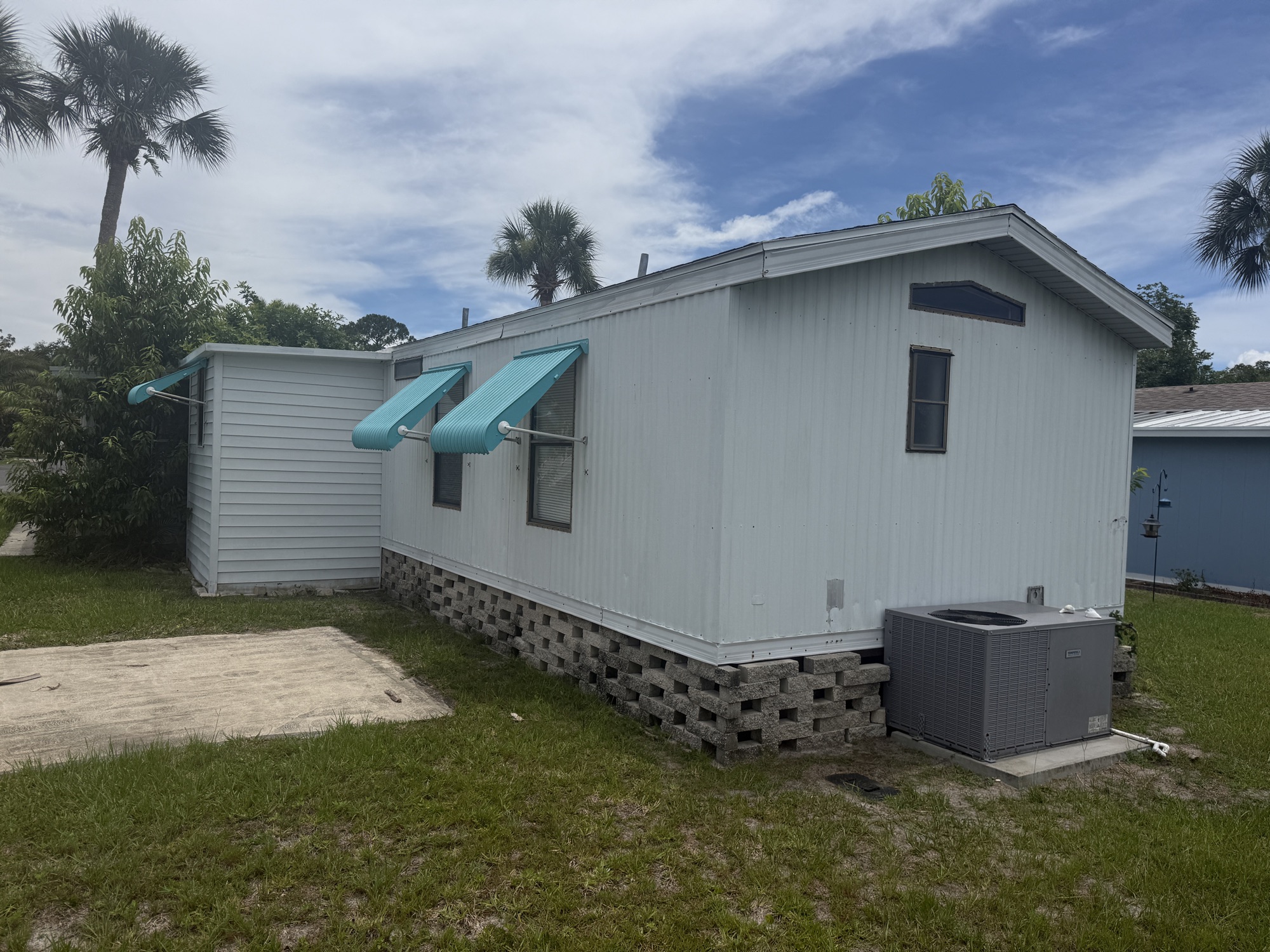 Side elevation with matching teal awnings and open lawn